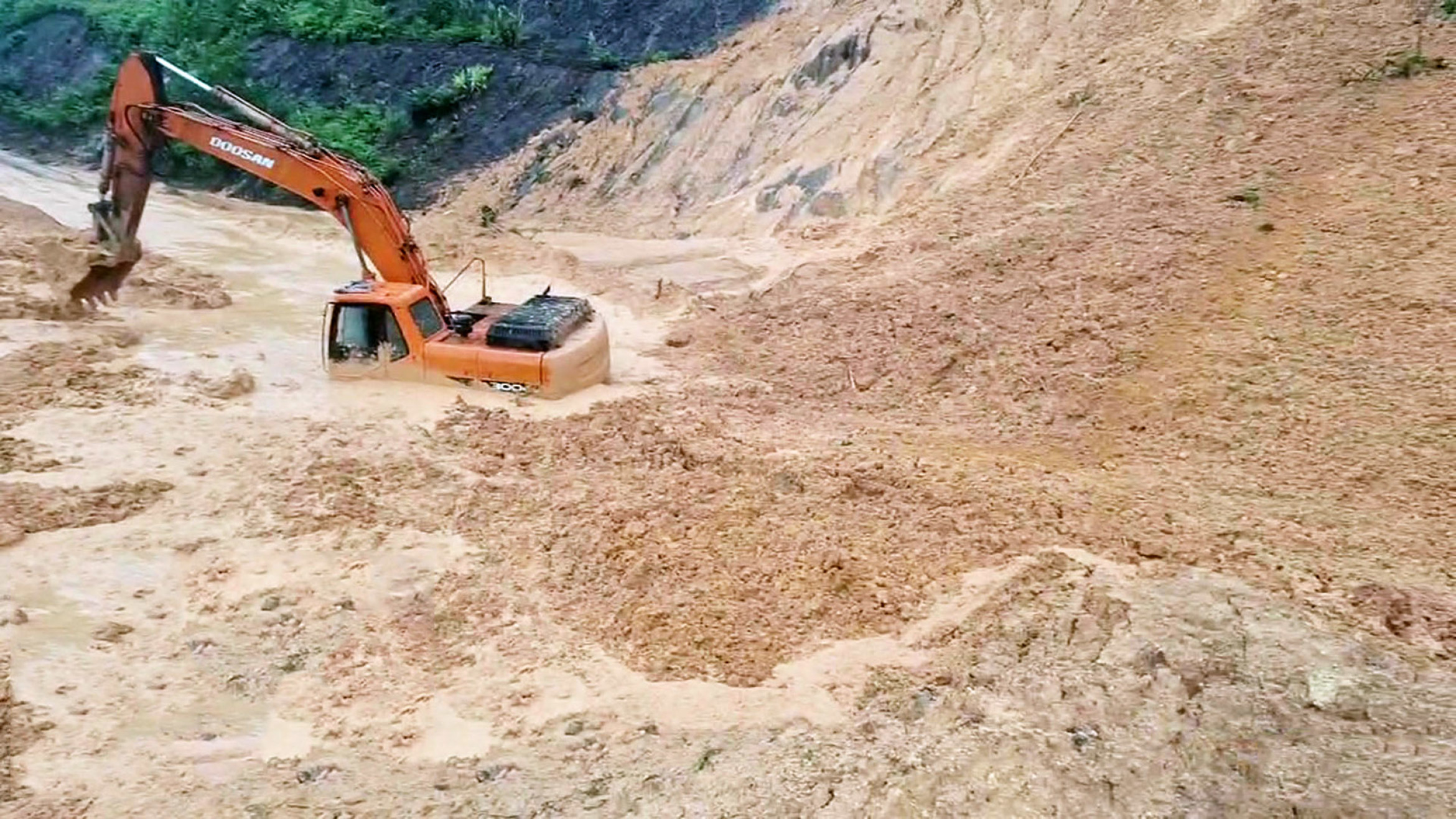 挖掘机正在清理泥土时,山坡突然崩塌轰然倒下